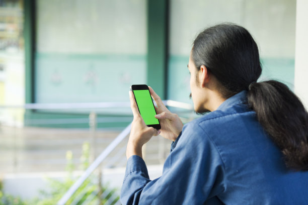 年轻的泰国男子用智能手机在户外做网上银行图片下载