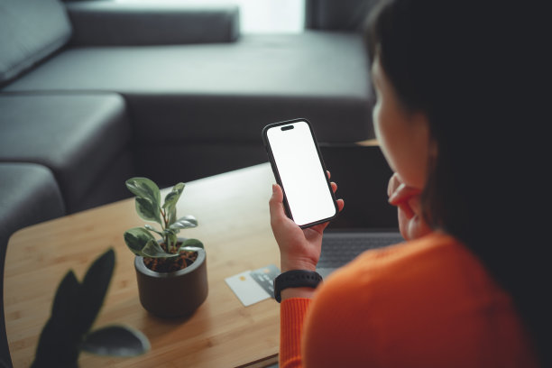 女子手持智能手机与白屏幕的模型在客厅。图片下载