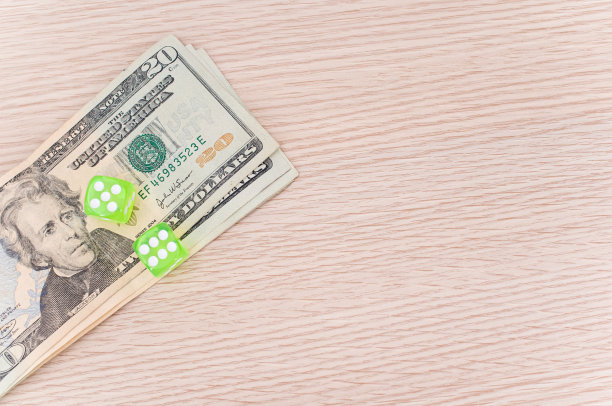 木制桌上放着美元钞票和绿色骰子图片下载