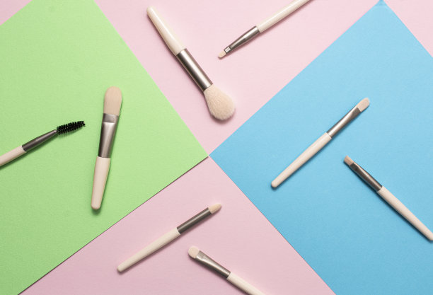 一套化妆刷在粉红色，蓝色，绿色的背景。俯视图，平面布局。图片下载