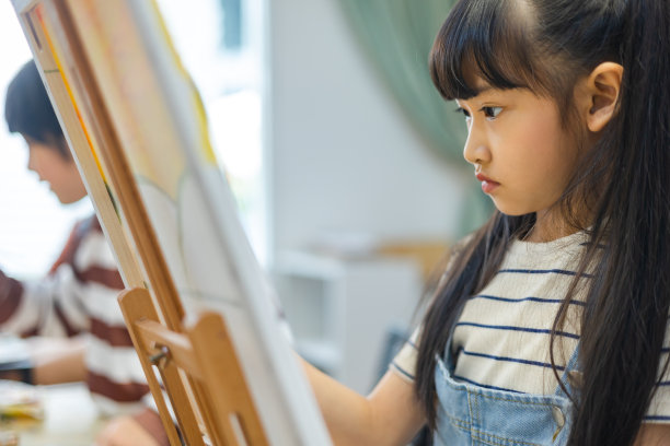 一群孩子在教室里画画，小女孩开心有趣地学习和玩在画布上画丙烯色。小女孩快乐有趣的学习和玩在纸上画画在小学。图片下载