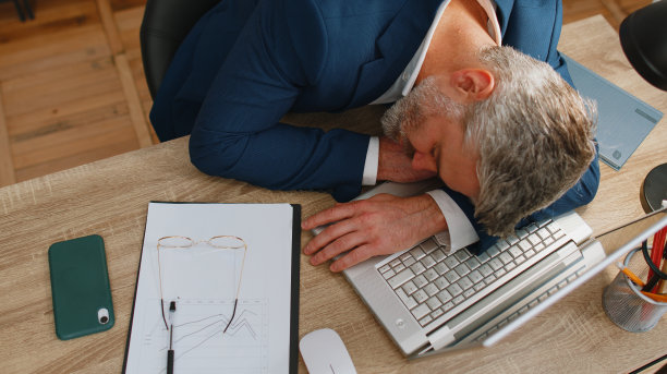 无聊疲倦昏昏欲睡的商人在办公桌上的笔记本电脑上例行工作后睡着了图片下载