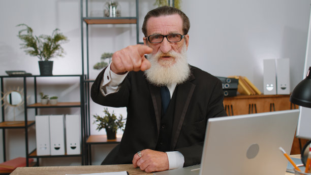 在办公室笔记本电脑上工作的商人指着相机，带着快乐的表情做出选择图片下载