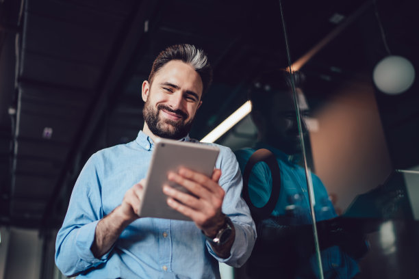 办公室里带着装置的成年微笑男人图片下载