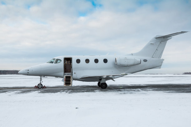 冬季机场停机坪上的现代白色私人飞机，舷梯门打开图片下载