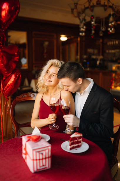 年轻的男人和女人在餐馆约会坐在桌子上拿着酒杯喝红酒欢呼调情。图片下载