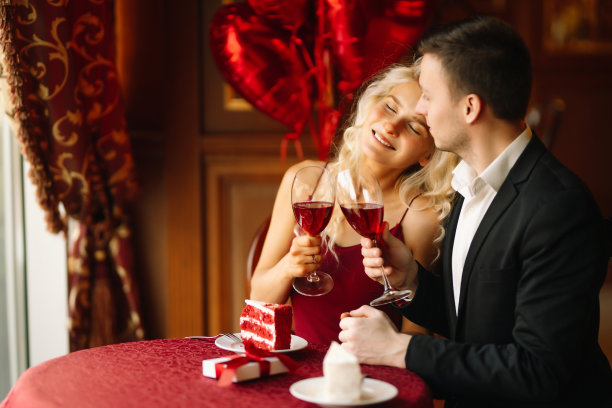年轻的男人和女人在餐馆约会坐在桌子上拿着酒杯喝红酒欢呼调情。图片下载