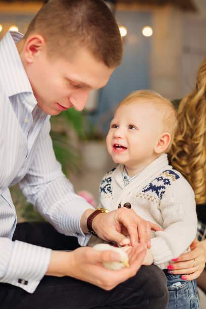 爸爸抱着一只小鸡，穿着漂亮衣服的小儿子看着他图片下载