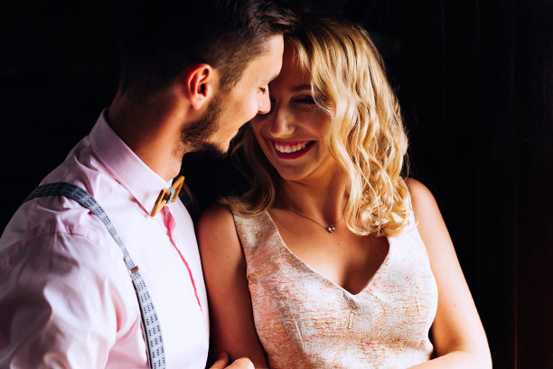 男孩温柔地拥抱着他的女朋友，她对着黑暗的背景真诚地笑了起来图片下载