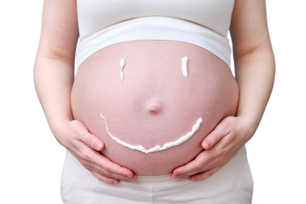 在一个孕妇的肚子上以微笑的形式出现的奶油，工作室拍摄，孤立在白色背景上图片下载