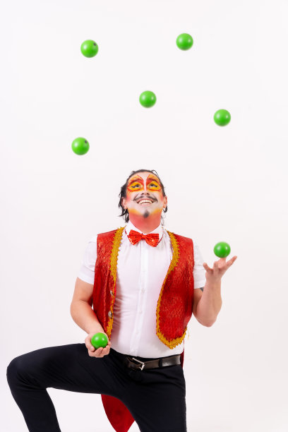 微笑的杂耍者杂耍白色背景上孤立的绿球图片下载