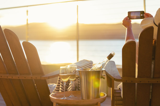 女人在水上平房的躺椅上放松和喝酒。图片下载