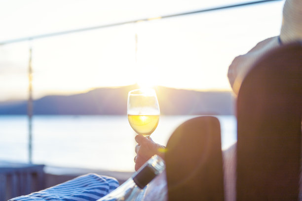 女人在水上平房的躺椅上放松和喝酒。图片下载