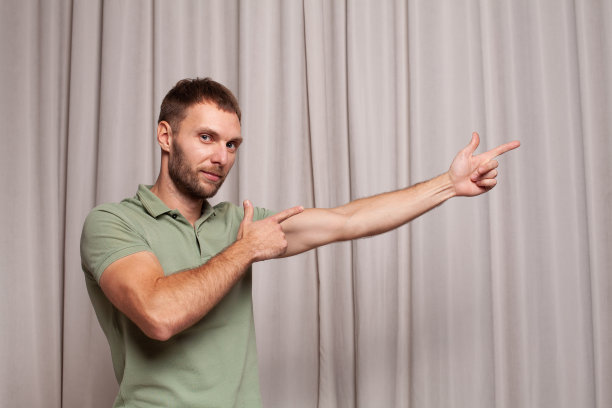 肖像自信的成年男子在绿色t恤指向米色背景图片下载