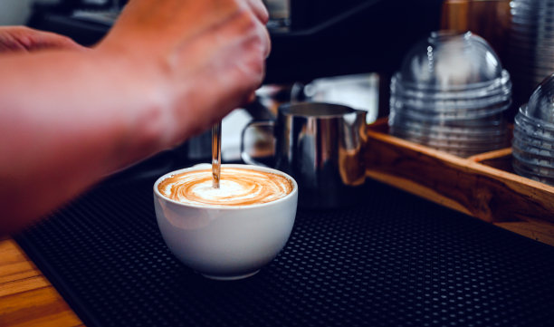 近距离的咖啡师的手在咖啡店准备蒸汽牛奶的一杯咖啡卡布奇诺菜单。图片下载