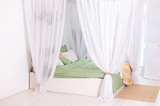 斯堪的纳维亚风格的现代白色卧室，床上有流动的白色窗帘。室内波西米亚设计的卧室，舒适的床与枕头，复制空间。图片下载