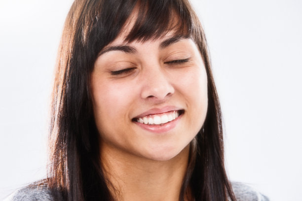 美丽的年轻女子与长黑发微笑安详，她放松与她的眼睛闭上图片下载