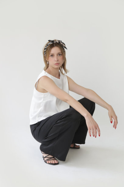 一系列的工作室照片，年轻的女模特在黑白丝绸装备，无袖上衣和宽腿裤图片下载