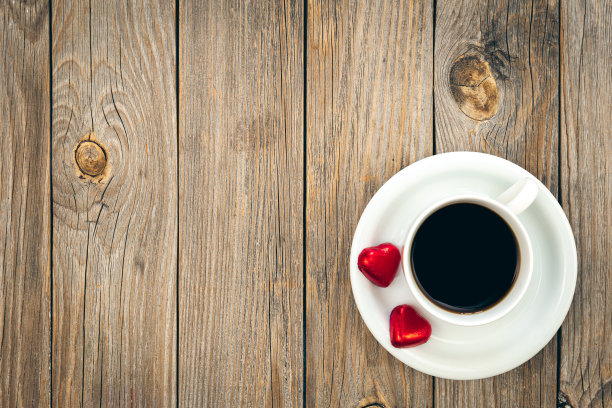 一杯咖啡和心形巧克力在木制背景，俯视图。图片下载