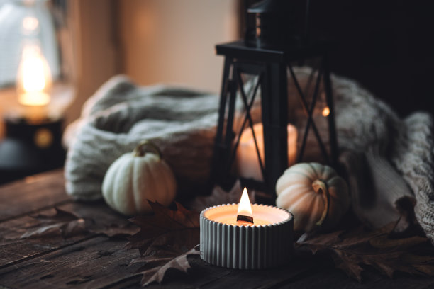 芬芳的蜡烛，南瓜，羊毛衫，树叶，肉桂组成舒适的秋天。在一个灰色的秋天的早晨，芳香疗法，舒适和放松的家庭气氛。木质背景特写。图片下载