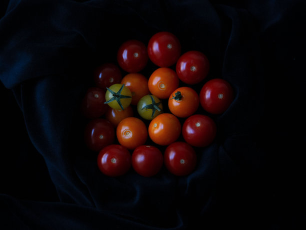 红色、橙色和绿色的西红柿配上黑色的背景图片下载