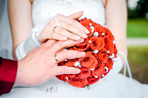 新娘和新郎的手放在新娘捧花上图片下载