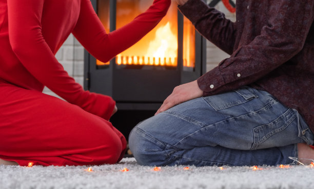 相爱的男女在家里约会，坐在火炉旁，舒适的地毯上燃烧着火焰。情人节，幸福的情侣，爱情故事，人际关系图片下载