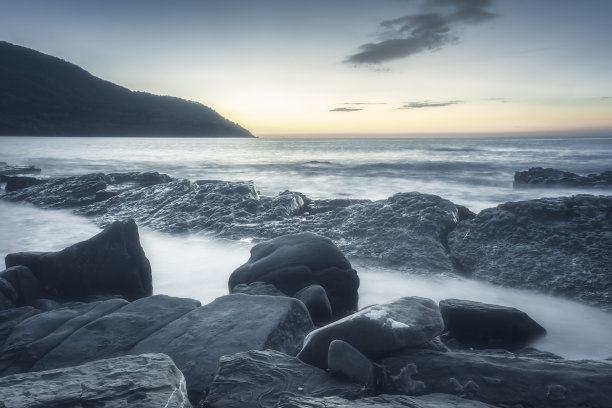 夕阳在蓝色的时刻出现在地平线上，前景是悬崖，理解一个假日的概念图片下载