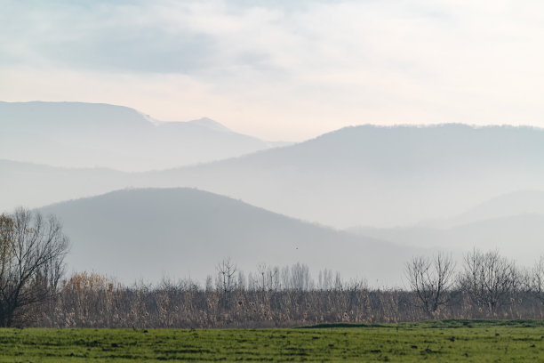 照片的草原和轮廓的山脉在日落的雾霾图片下载