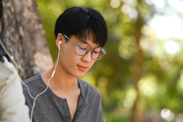 年轻的亚洲男子的照片读书和听音乐耳机与他的女朋友。图片下载