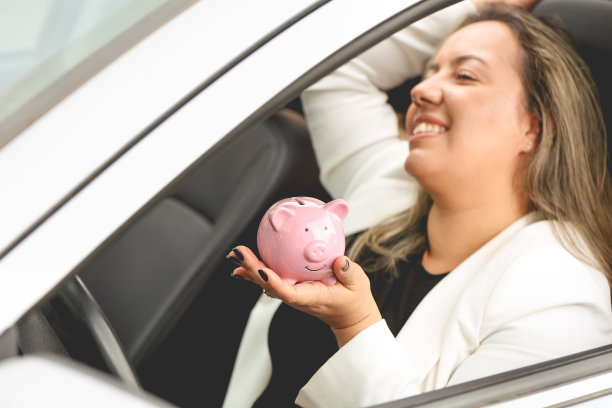 一个非常快乐的女人在车里拿着一个存钱罐。图片下载