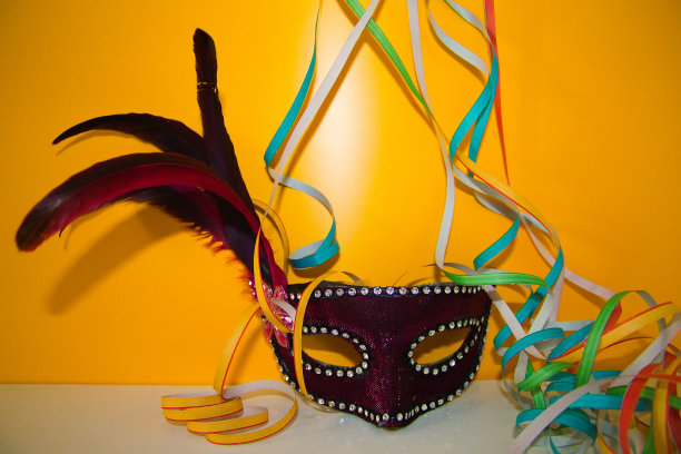 紫色嘉年华面具与五彩纸屑和卷纸在黄色背景图片下载