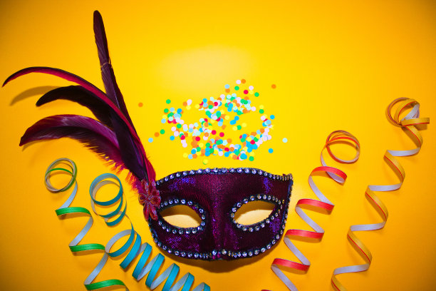 紫色嘉年华面具与五彩纸屑和卷纸在黄色背景图片下载