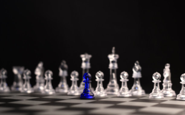 一个孤独的蓝色棋子面对水晶白色棋子作为对手的选择性焦点图片下载