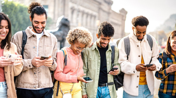 多元文化的快乐朋友一起玩手机在大学校园-科技生活方式的概念与年轻的男孩和女孩分享有趣的视频在智能手机设备-明亮生动的过滤器图片下载