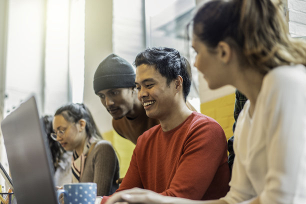 年轻的同事多民族团队计划一个新的创业-快乐的计算机程序员在创意联合办公办公室的一个新项目-明亮的过滤器，专注于亚洲人的脸图片下载
