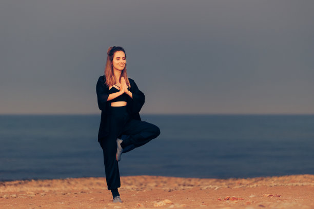 快乐微笑的女人放松在海滩上的瑜伽姿势图片下载