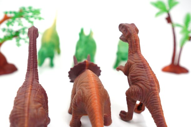 这张照片展示的是一个玩具模型，白色背景上有一群棕色和绿色恐龙面对面。图片下载