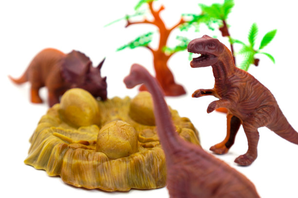 图中是一组棕色恐龙模型和白色背景下的恐龙蛋。图片下载
