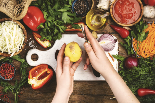新鲜的素食素食材，蔬菜，香料，草药健康饮食在质朴的木制厨房餐桌与砧板。女人用手削土豆皮。饮食、清洁、舒适的烹饪理念图片下载
