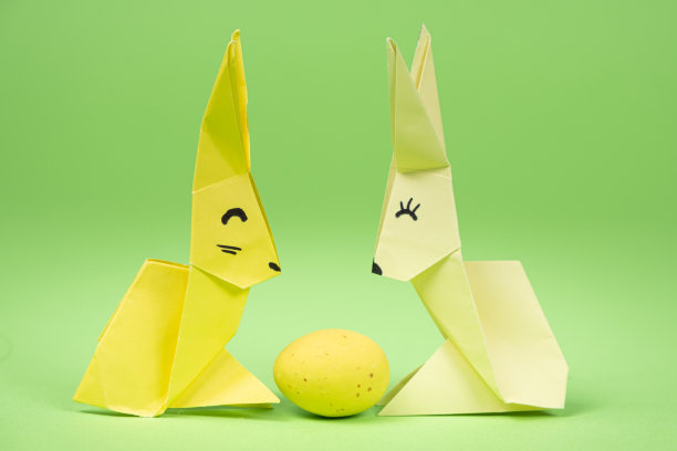 复活节折纸-两个纸兔子和一个鸡蛋，绿色背景。节日手工，自己动手图片下载