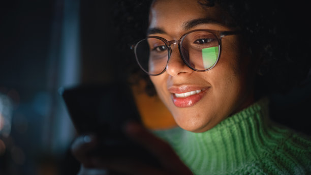 使用智能手机的多种族黑人女孩的特写肖像。收到好消息，成功的电子商务销售，新的自由订单电子邮件，股票正在增长，社交媒体约会概念。图片下载