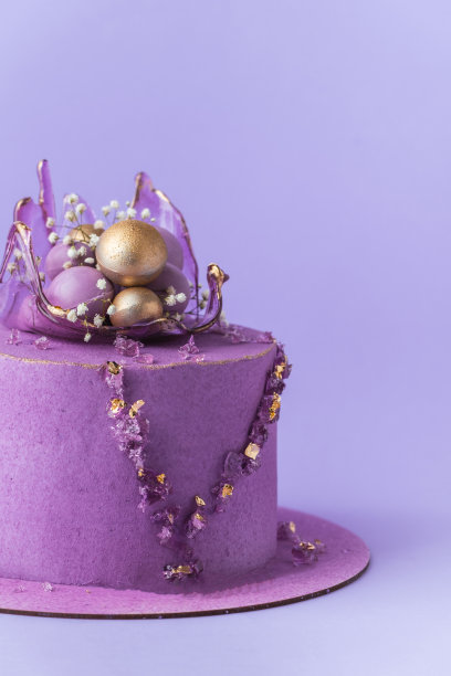 婚礼蛋糕，紫色奶油奶酪糖霜装饰焦糖花瓶和金色巧克力球在紫色的背景。粉红色巧克力天鹅绒涂层的豪华周年蛋糕图片下载