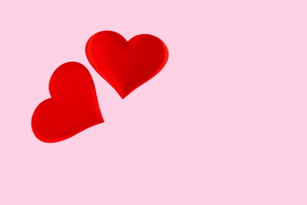 红色的心散布在粉红色的背景。情人节图片下载