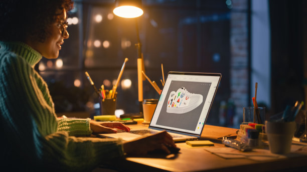 拉丁女艺术总监回顾3D模型的鞋子，在阁楼家居客厅的笔记本电脑上工作。艺术家女孩制作可视化在特殊的软件。平面设计师概念。图片下载