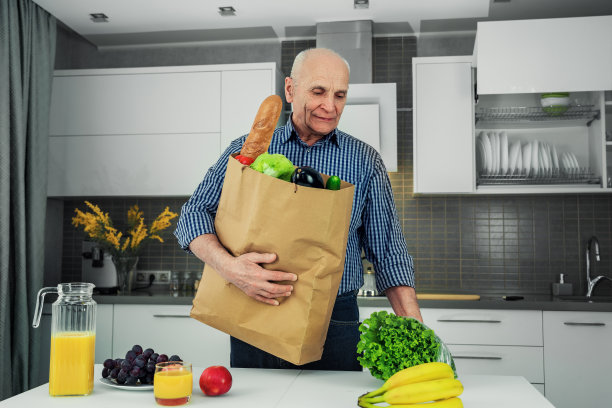 老人的肖像快乐的男子拿着纸袋与供应。图片下载