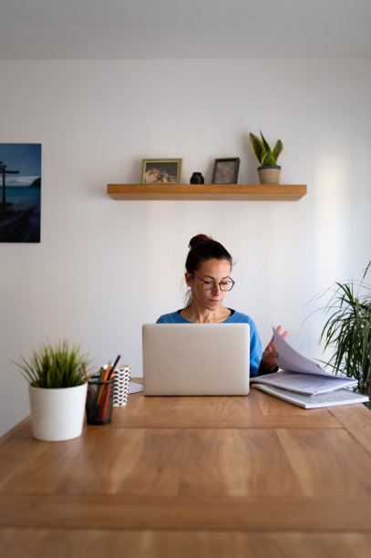 前视图的白人黑发妇女在家里工作在她的笔记本电脑。图片下载