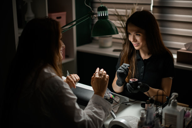 漂亮的女人正在美容院的美甲师做指甲图片下载