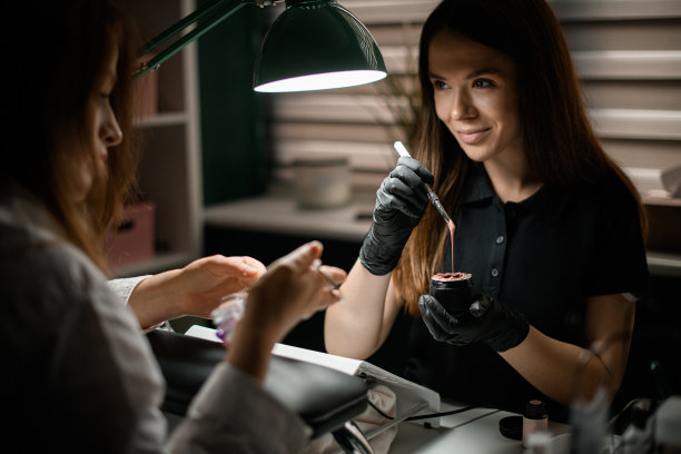 在美容院，微笑的美甲师拿着罐子和刷子图片下载