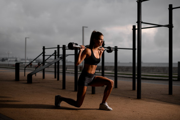 在她的肩膀上拿着杠铃的女运动员的观点。户外训练图片下载